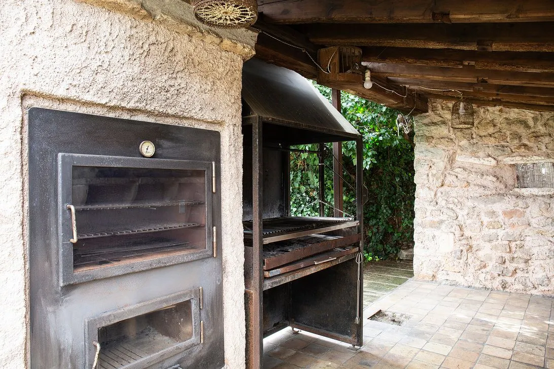 A stone oven and grill, built in, half under cover