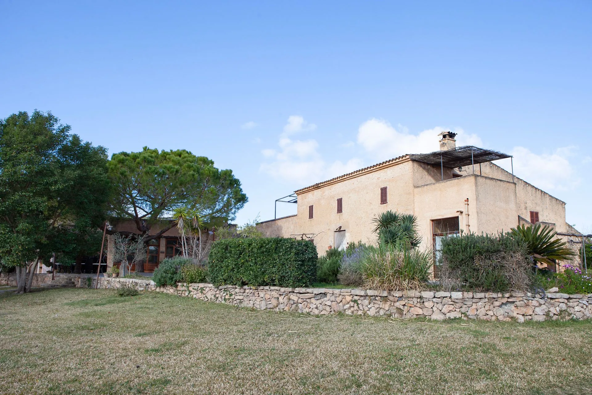 The stone finca behind its boundary wall, set back in the fields under a wide sky