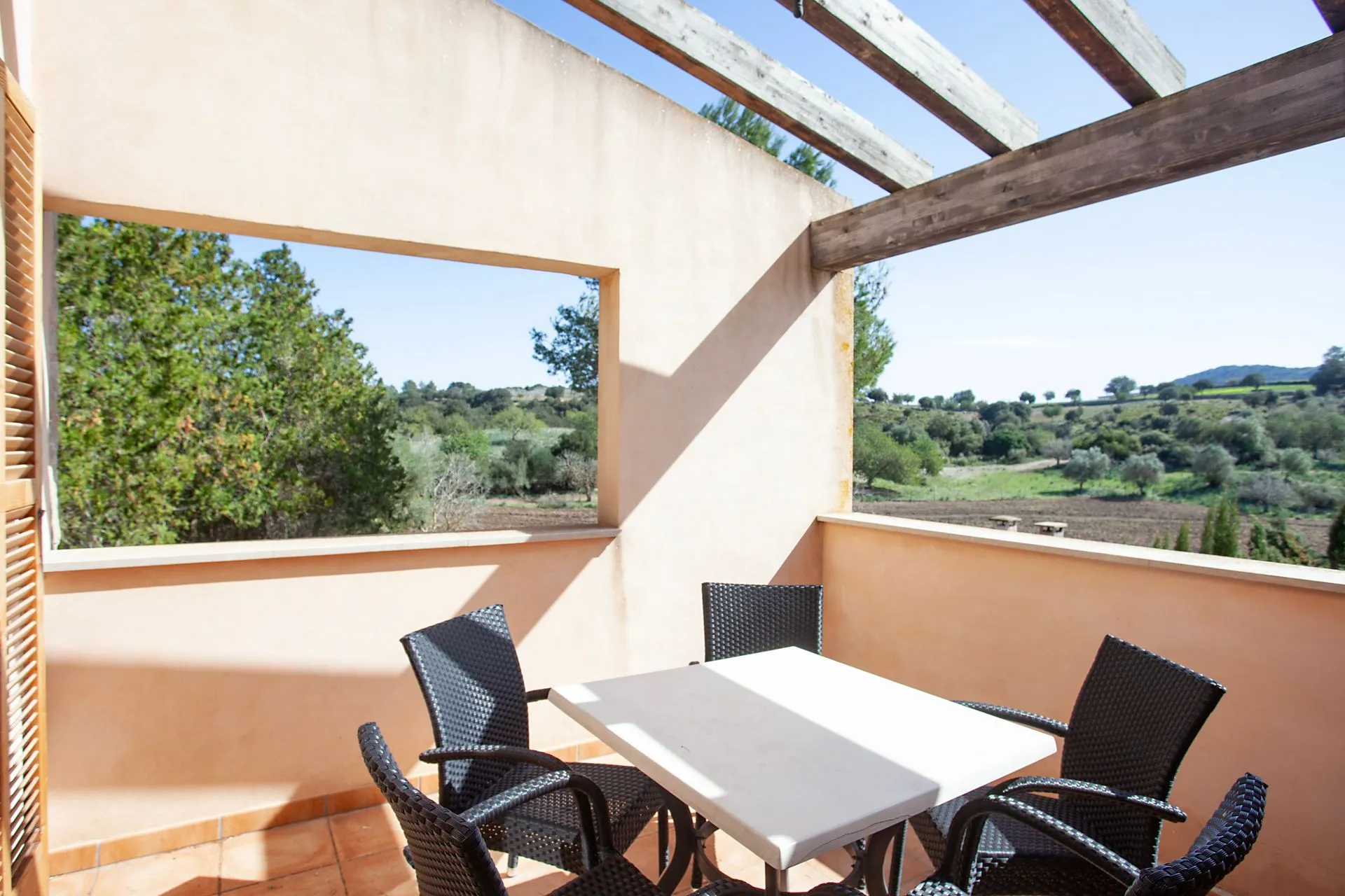 A balcony with table and chairs beside a wide window
