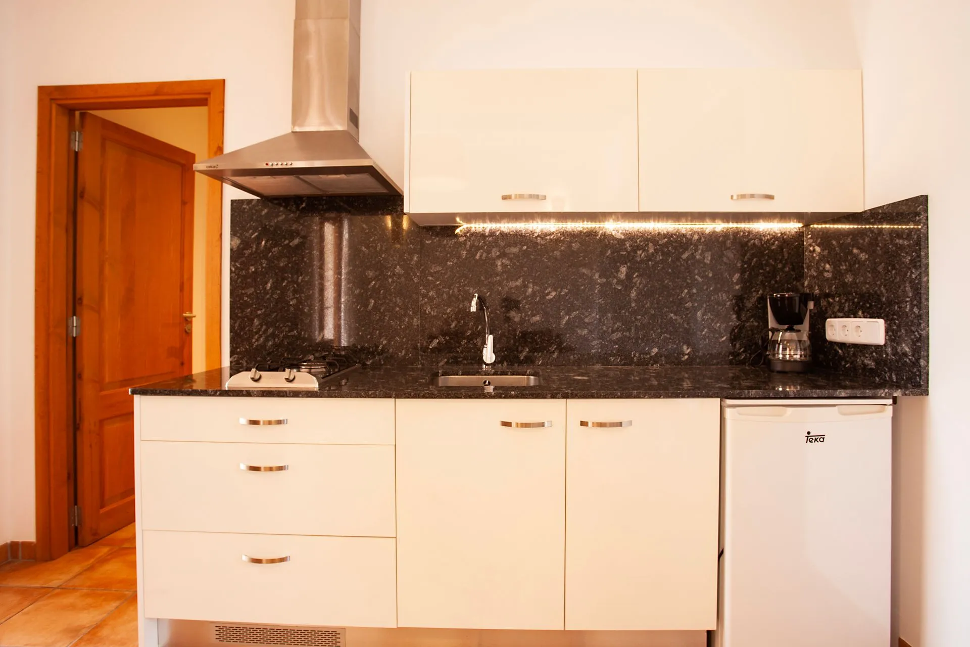 A kitchen, white cabinets and black granite tops