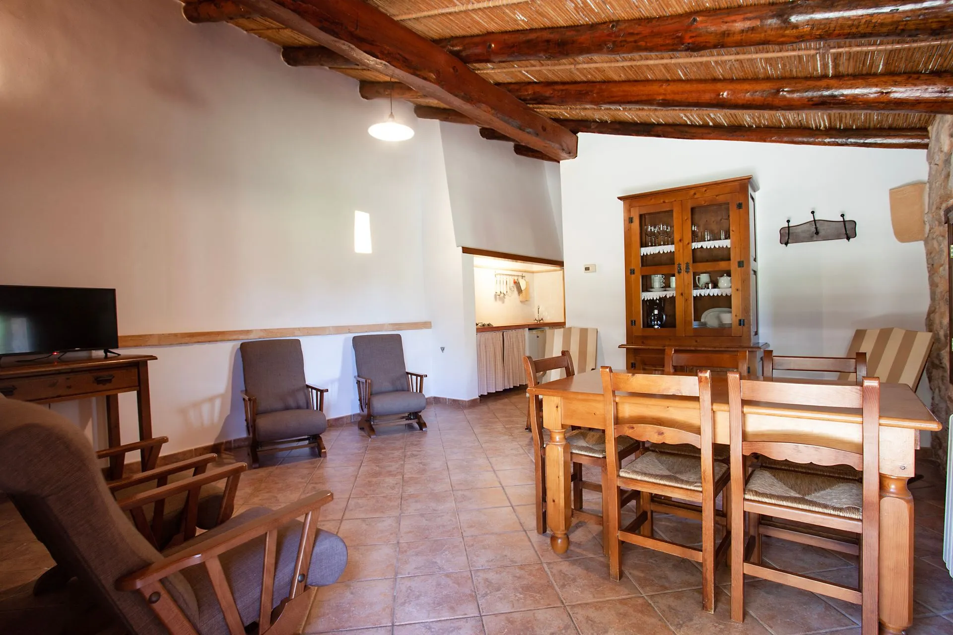 A living room with a table and chairs, rustic furniture and a television
